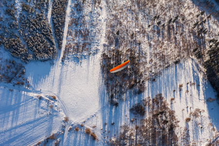 aerial view of paramotor flying over the forest in winter in Polandの写真素材
