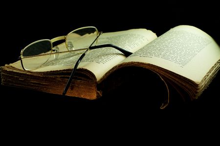 old book with a glasses. made on dark background with a Light brushの写真素材