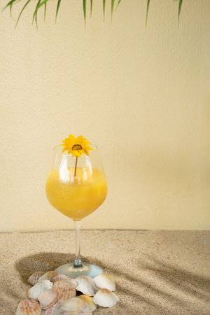 summer sunny beach idea with glass of vibrant yellow cold drink.tropic shadows on a sandy beige...