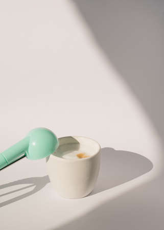 white background with shadows, cup of coffee and mint green scoop for ice cream balls.aesthetic concept for end of summer or welcome autumnの写真素材