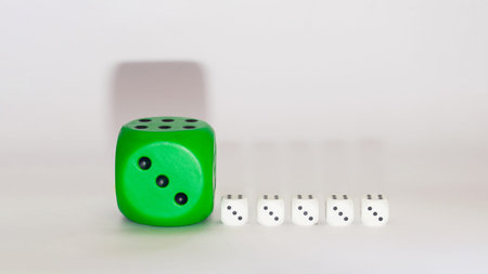 green dice next to white little white dices on a white background with shadows.still life visual...