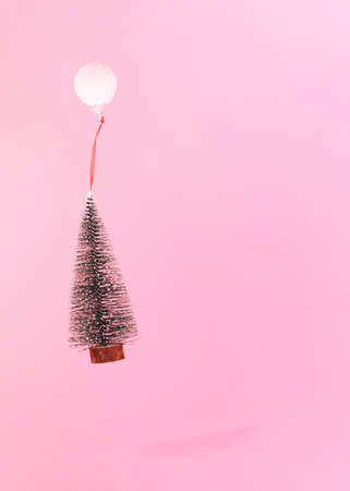 Christmas tree flying held by snowy white bauble.holidays winter concept idea.Party advent daysの写真素材