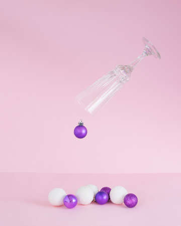 Christmas baubles coming out of champagne glass.Ornaments vivid violet and snowy white on a pink background.New Year holidays conceptの写真素材