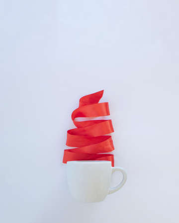 Christmas tree made of red satin strap coming out of coffee cup. Holidays winter design.White and red New Year concept ideaの写真素材