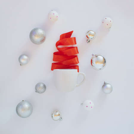 Christmas tree made of red satin strap coming out of coffee cup. Holidays winter design.White and red New Year concept idea with baubles all over.Flat layの写真素材