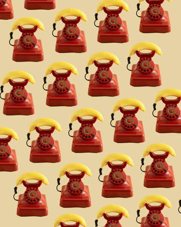 retro red telephone with yellow fresh banana imitating phone handset.aesthetic still design.communication or invitation pattern concept ideaの写真素材