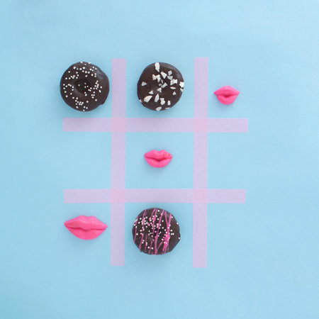 Doughnuts colorful playing Tick Tack Toe with pink kisses. Food aesthetic flat lay design idea....