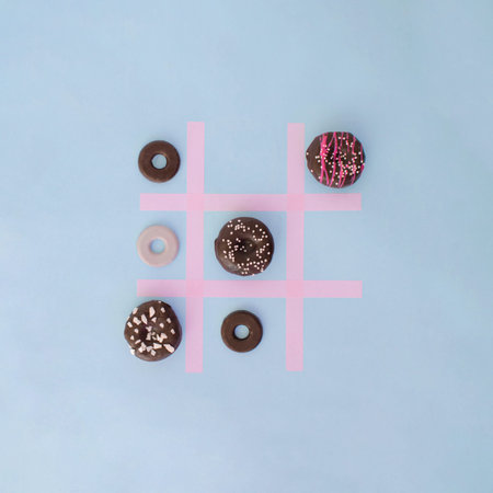 Doughnuts colorful playing Tick Tack Toe with round cookies. Food aesthetic flat lay design idea....