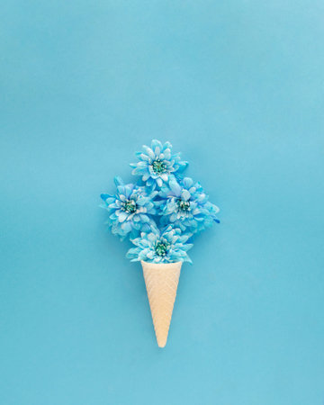 Ice cream cone with soft blue flowers like ice cream. Spring summer sunny days concept idea. Flat...