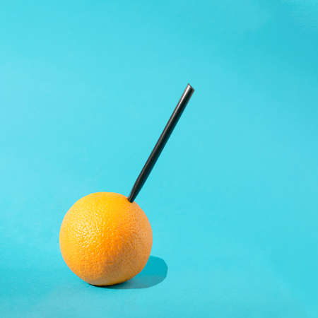 Orange minimal with black straw. Juicy fruit minimal concept. Summer sunny day on a sky blue background. Refreshment ideaの写真素材