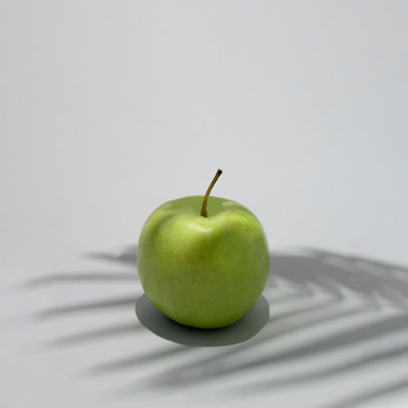 Apple green on a sunny summer day. Palm shadow. Aesthetic fruit concept. Food abstract design. Healthy diet vacation ideaの写真素材