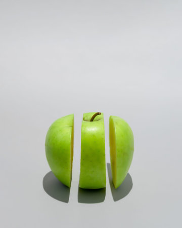 Apple green cut in three peaces. Sunny summer shadow. Aesthetic fruit concept. Food abstract design