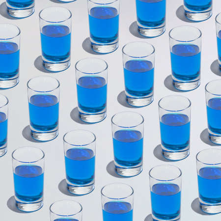 Blue transparent drink in a glass. Pattern aesthetic summer design. Sunny day drink partyの写真素材