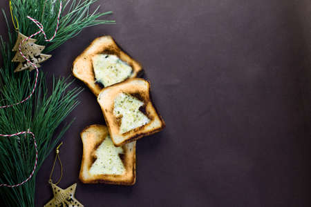 ruddy toasts with New Year and Christmas symbols lie on a brown plain background, next to there is a green Christmas tree and Christmas decorations, there is space for textの写真素材