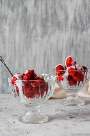 red strawberries poured with white cream on a glass in a dessert cupの写真素材