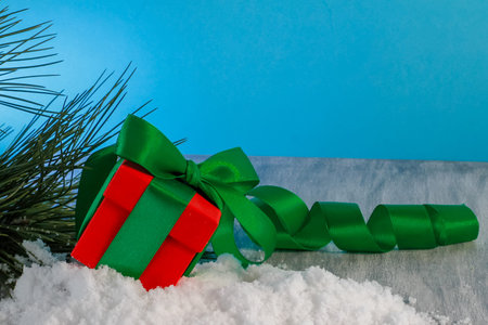 a christmas gift in a red box with a green one lies on the table, the girl stretches out her hand...