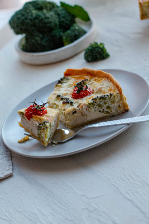 Quiche pie with chicken and sun-dried tomatoes on a light background, spices are scattered nearbyの写真素材