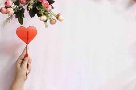 caramel pink heart on a pink background next to red flowersの写真素材