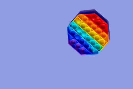 the rainbow-colored pop toy lies on the background. space for textの写真素材