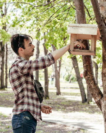 a man in a plaid shirt puts nuts in a feederの写真素材