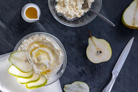 cottage cheese poured with syrup with slices of fresh pear, dark background, top viewの写真素材