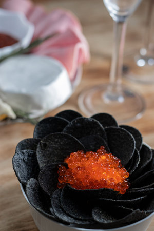 Black potato chips with red caviar. Close-up