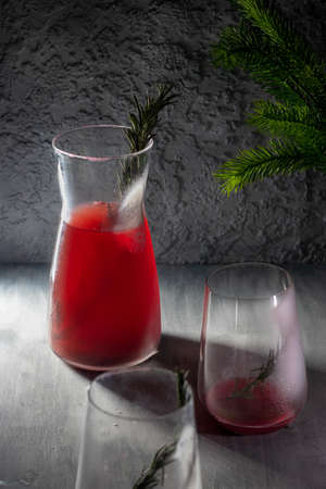 Red drink in a glass decanter. next to two empty glassesの写真素材