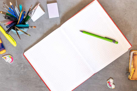 an open notebook with a pencil on it. Nearby is a glass with pens and pencilsの写真素材