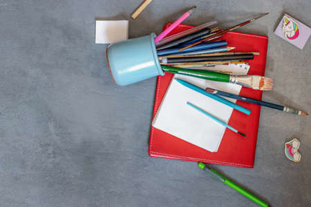 an overturned glass with pens and pencils lies on a red terraceの写真素材