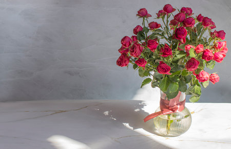 Bouquet of red roses in a glass vase, on a marble backgroundの写真素材