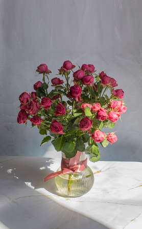 Bouquet of red roses in a glass vase, on a marble backgroundの写真素材