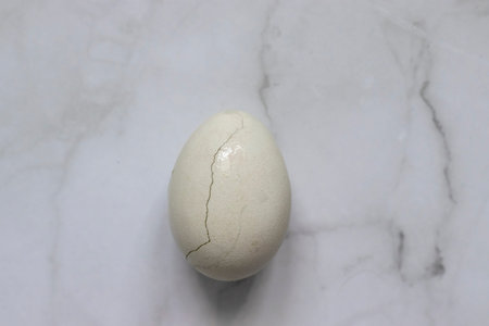 Three white eggs lie on a marble background