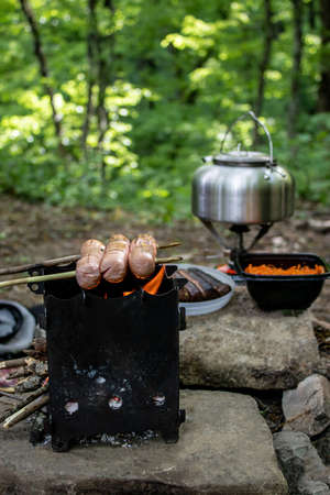 Sausages on wooden skewers are fried on an open fire. Food on the hike. Outdoor foodの写真素材
