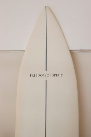 A beige surfboard stands against the wall. The inscription on the board of Freedom of spiritの写真素材
