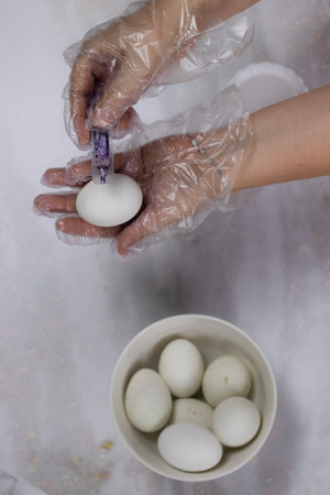 Girl paints Easter eggs lilac