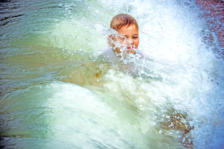 happy boy at the sea lying in  sand and wavesの写真素材