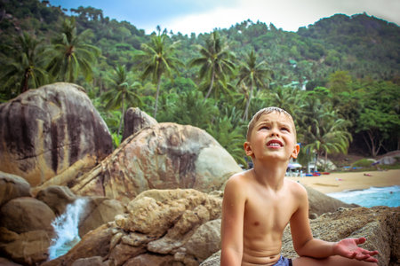 Upset boy waits for the rain on beach of tropical island Koh Samui