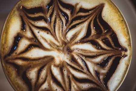 Cup of coffee latte with design art in froth, on a wooden table. Close up macroの写真素材