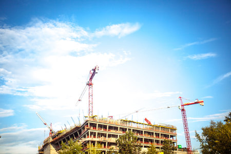 Cranes and building construction site against blue sky