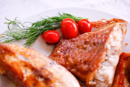 Tasty baked fish with cherry tomatoes and fresh herbs on plateの写真素材