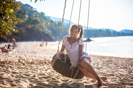 woman sitting on the swing at paradise beachの写真素材