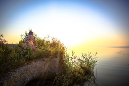 Young man fishing at misty sunrise in the morning. の写真素材