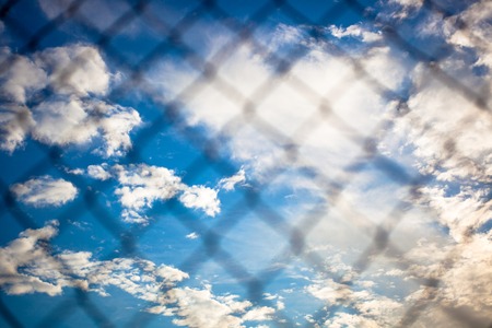 Chain Link Fence With Blue Sky Background and cloudsの写真素材