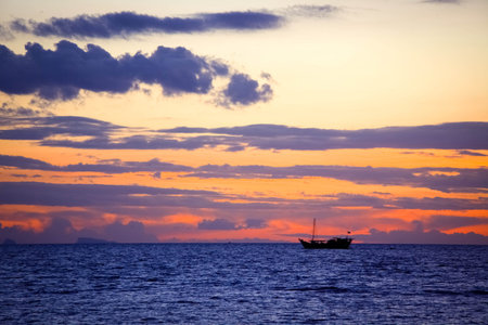 Amazing sunset over the beautiful sky with clouds, rippling waters of the sea and sailing ships. Koh...