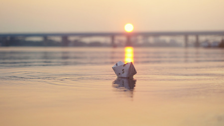 paper boat on the water during beautiful sunset with reflection sun in the sea. Bridge  the backgroundの写真素材
