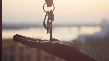 Hand holding three metal keys on sunset background, Industrial backdrop