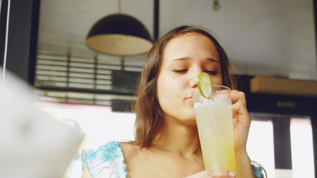 Young woman using smartphone and drinking beverage in a cafe