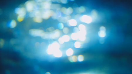 Beautiful underwater sea scene view with natural light rays, shining through the waters glittering and blurred bokehの写真素材