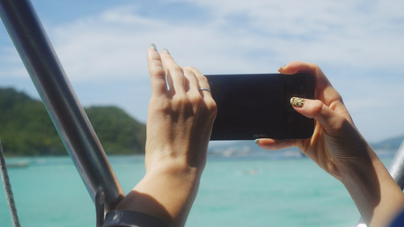 Close up of woman using mobile smart phone on the beachfront during vacationの写真素材