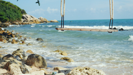 Tropical Island Beach and Tree Swing. Splashing waves in the Sea at stones on beautiful background on the blue sky. Paradise at Koh Samuiの写真素材